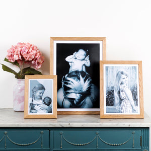 solid oajk photo frames, gallery wall wooden frame and A5 frame, A4 oak frame and an A3 oak frame with flower decoration on a sideboard